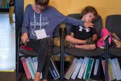 A mother uses one arm to steady her sleeping son while using the other to transfer notes from phone to paper as they both wait for another child to finish her performances in Generations PAC dance exhibition during Fourth Friday. My Final Photo for Sept. 25, 2015.