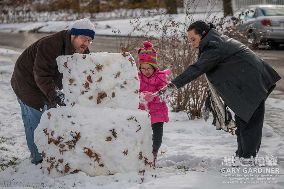 A family shapes their first snowman of the season in their front yard. My Final Photo for Nov. 27, 2013.