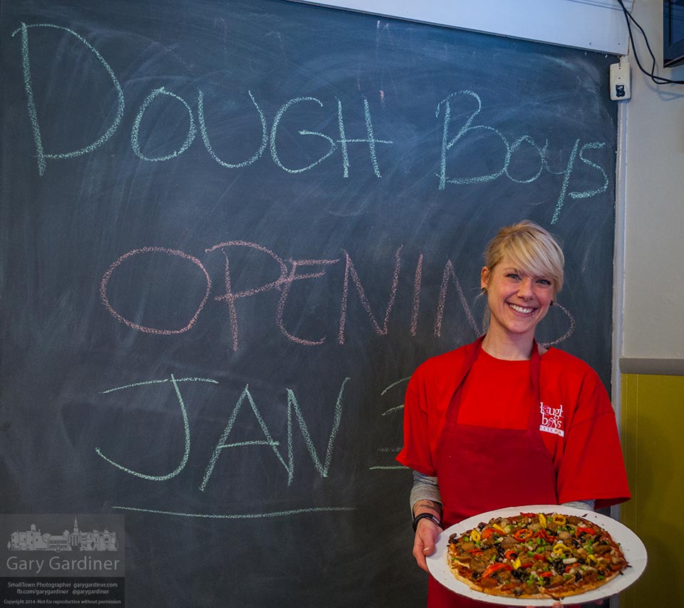 Cook and server Beth Erler holds a deluxe pizza in front of the blackboard announcing the grand opening of Doughboys Pizzeria on East Main Street in Uptown Westerville. My Final Photo for Jan. 30, 2014.