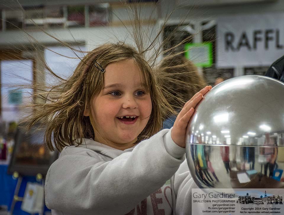 Static electricity from a Van de Graaff generator causes a young girl's hair to stand on end at the Otterbein Physics Lab table at Starry Nignt, A STEM-learning exposition at Westerville South. My Final Photo for April 6, 2014.