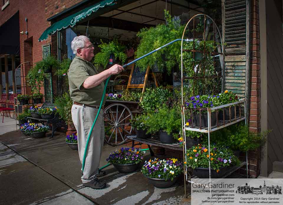 One of the sure signs of warmer weather and a bright Spring is Dave Talbot watering plants in front of his flower shop on North State Street. My Final Photo for April 10, 2014.