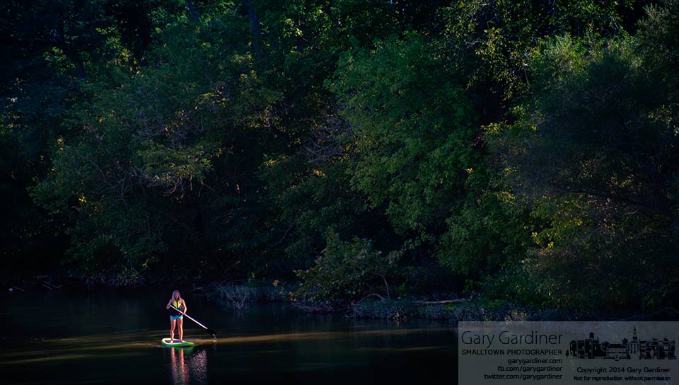 A paddle boarder glides into a slice of light cutting through trees along the west bank of alum creek near the Main Street bridge. My Final Photo for August 29, 2014.