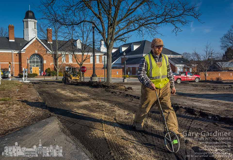 A construction workers measures the dimensions of asphalt surfaces behind city hall after a milling machine removed old asphalt in preparation for rebuilding and expanding the lot. My Final Photo for Feb. 10, 2014.
