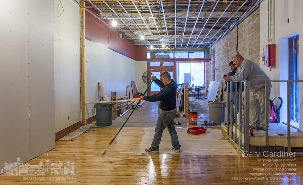A flooring worker applies the first of three coats of polyurethane varnish to the restored section of original 1880's maple flooring in Asterisk Supper Club in Uptown Westerville. My Final Photo for Nov. 12, 2015.