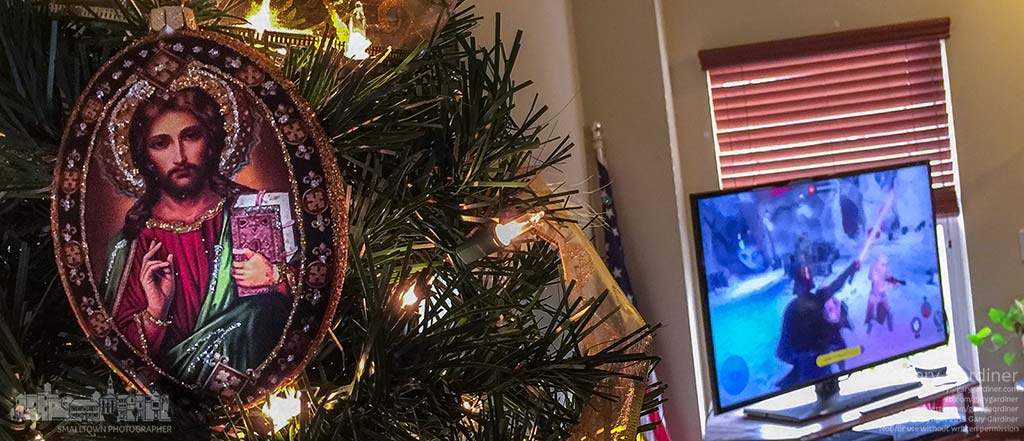 A religious icon of Christ hangs on a Christmas tree as a family plays a Star Wars video game on the new Sony Playstation they received as a gift Christmas morning. My Final Photo for Dec. 25.