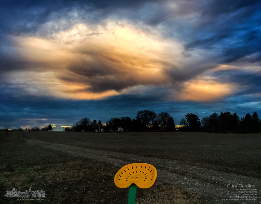 Late afternoon storm clouds shine brightly from the setting sun with a sickle mower sitting next to a road running the field at Yarnell Farms. My Final Photo for Dec. 16, 2015.