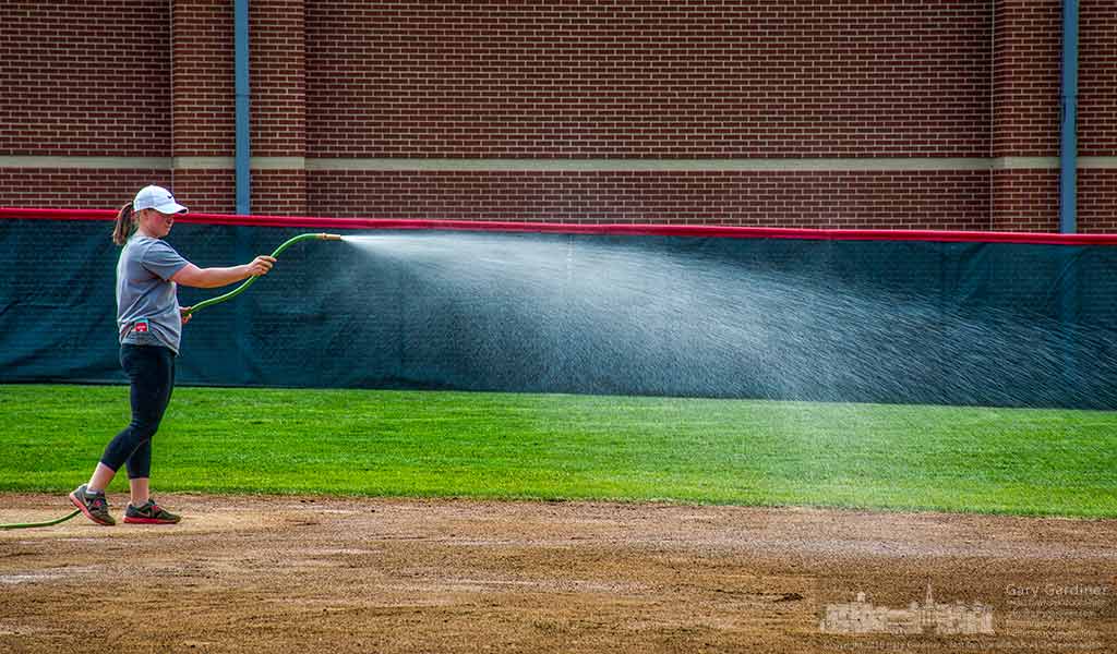 An Otterbein women's softball coach uses a water hose to water down the field after an earlier game. My Final Photo for March 23, 2016.