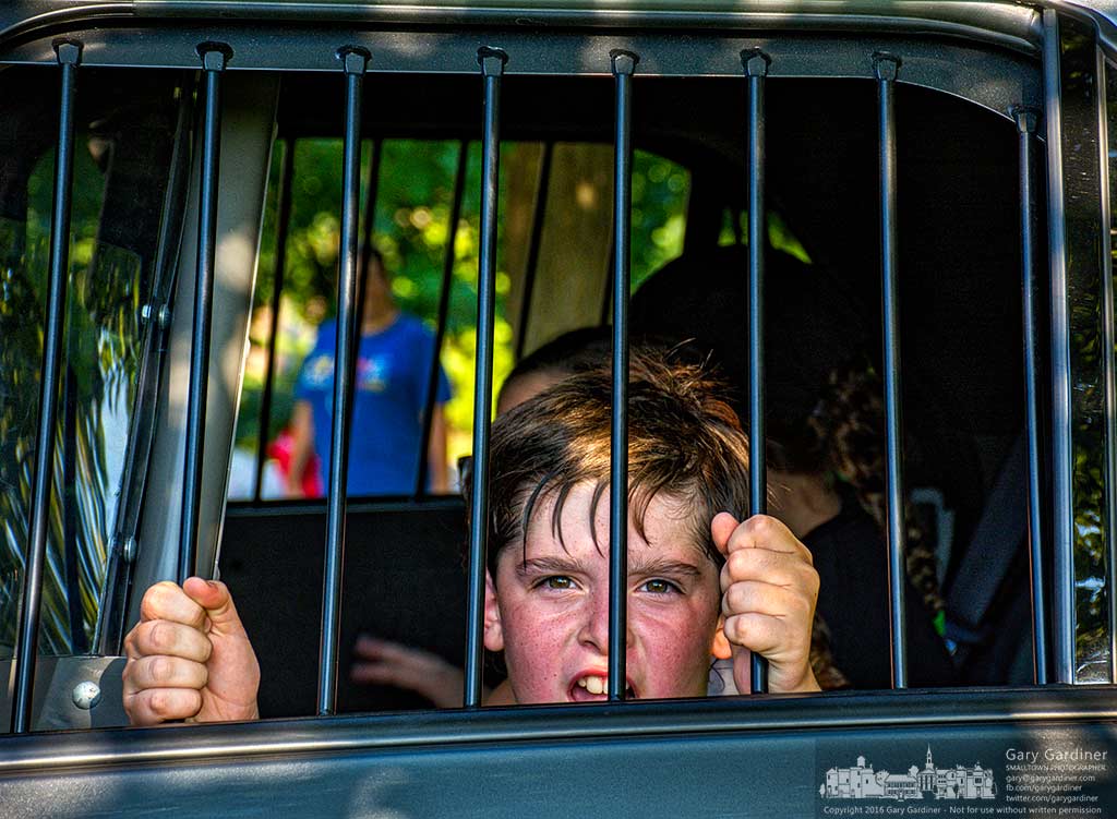 A youngster acts the role of a criminal from the back seat of a police car during National Night Out in Westerville, Ohio, Tuesday night. My Final Photo for Aug. 2, 2016.