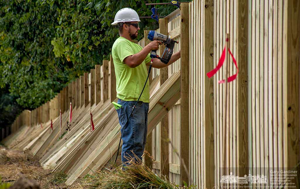 A worker nails boards to the inside of the privacy fence built around the site of the Aloft Hotel under construction at State and Heatherdown in Westerville, Ohio. My Final Photo for August 8, 2016.