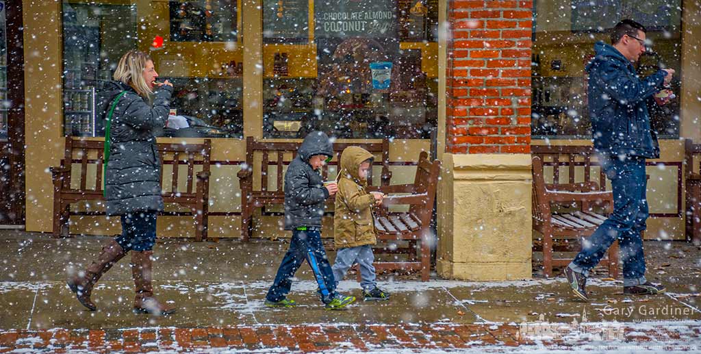 A family takes bites of Graeter’s ice cream as they walk back to their car during an afternoon snow storm in Uptown Westerville that clogged streets and slowed commuters. My Final Photo for Jan. 5, 2016.