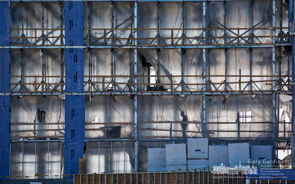 A construction worker is silhouetted inside plastic protective sheets covering the exterior of the Marriott Renaissance Hotel on Polaris Parkway in Westerville, Ohio. My Final Photo for Feb. 13, 2017.