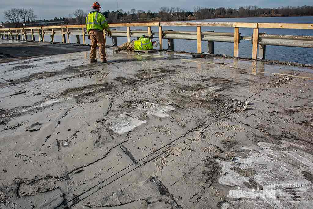 Puddles of gray mud formed from concrete sawdust and the water used to cool the cutting blades of high torque machines cover sections of the Smothers Road Bridge where contractors began the process of removing the old deck. My Final Photo for Feb. 16, 2017.