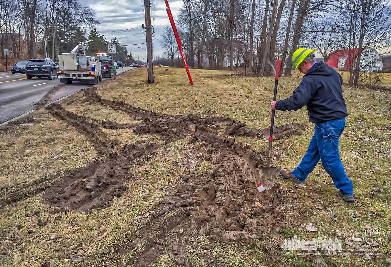 A contractor fills in ruts in the mud left behind when his bucket truck was retrieved after becoming stuck in the mud just off the roadway where a crew inspected overhead fiber optic cables as part of the reconstruction of Cleveland Ave near Schrock Road. My Final Photo for Jan. 22, 2018.