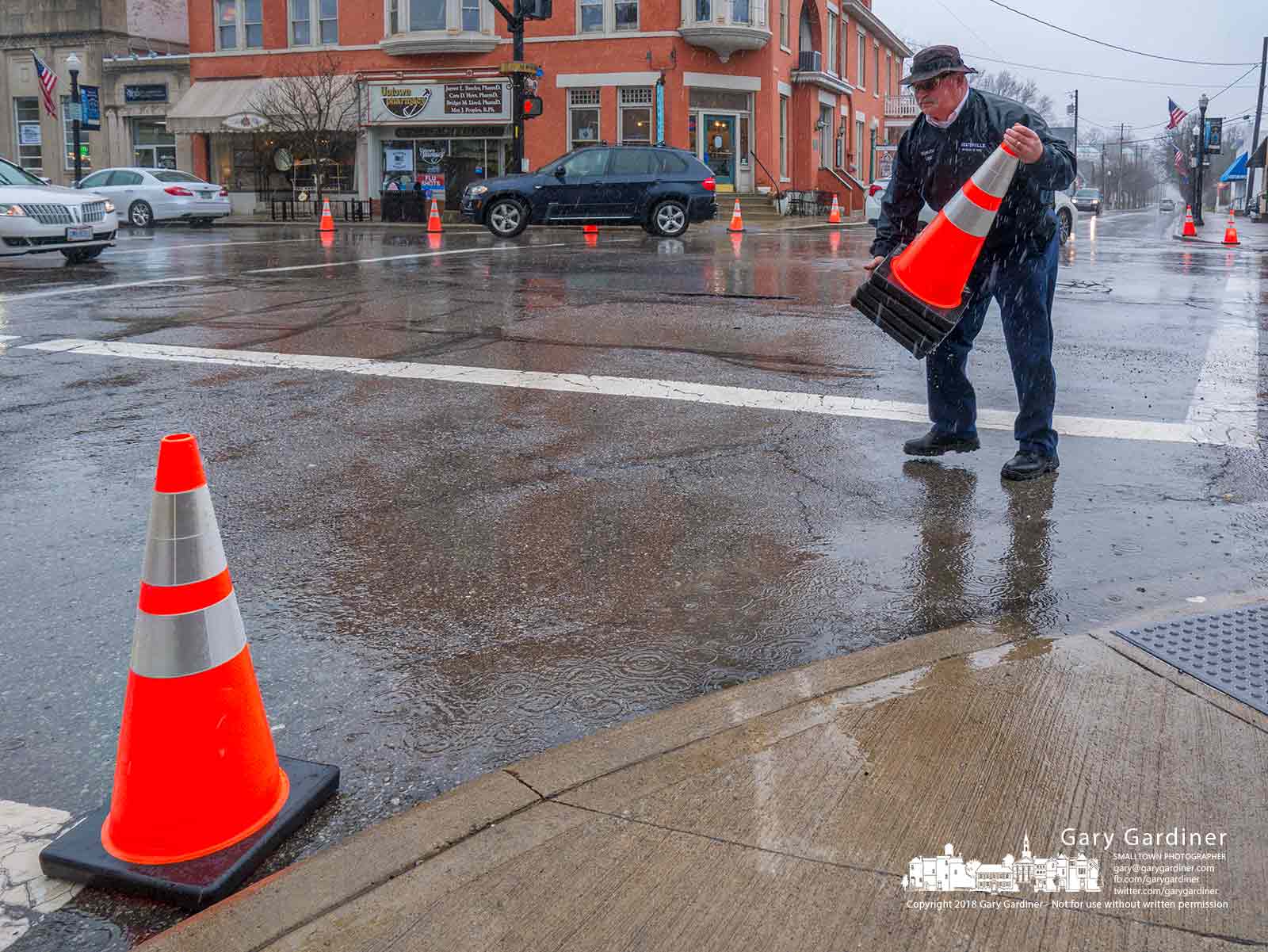 A Westerville firefighter retrieves traffic cones placed on the corners of State and Main to test the turn radius if the sidewalks were extended into bumpouts as proposed in the Uptown Streetscape plans. My Final Photo for March 1, 2018.