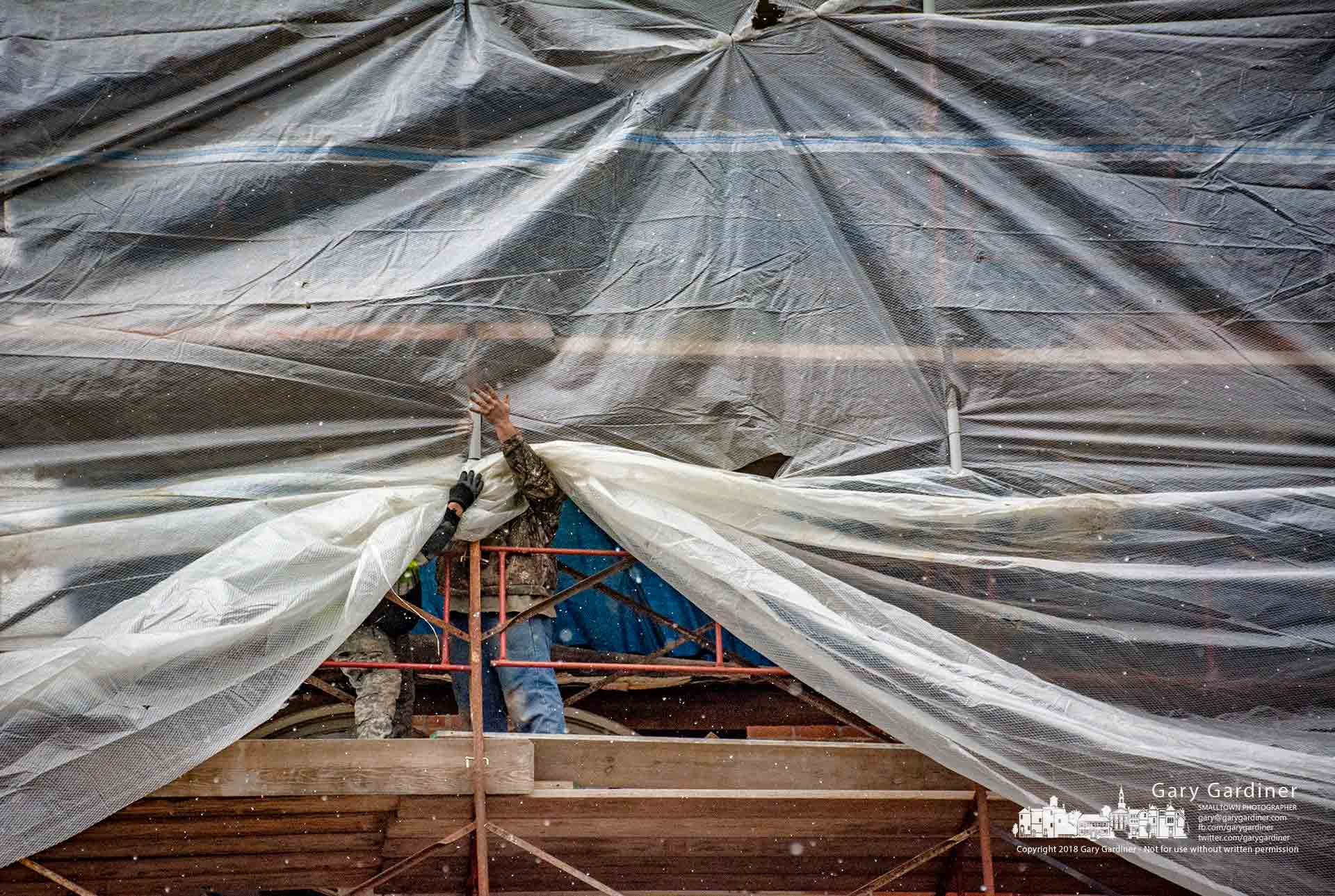 A restoration crew attaches reinforced plastic sheeting to scaffolding above Graeter's as a weather shield as they begin the process of repairing a section of the building after an earlier upgrade revealed problems requiring additional work before installing a new facade. My Final Photo for Dec. 5, 2018.