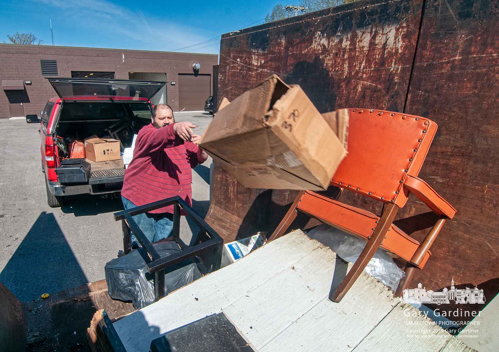 A man tosses a box of household waste into a trash container at the Blendon Township Service Department during the township's Community Cleanup Days where residents could get rid of old tires, medicines, trash, and documents for shredding. My Final Photo for April 27, 2019.