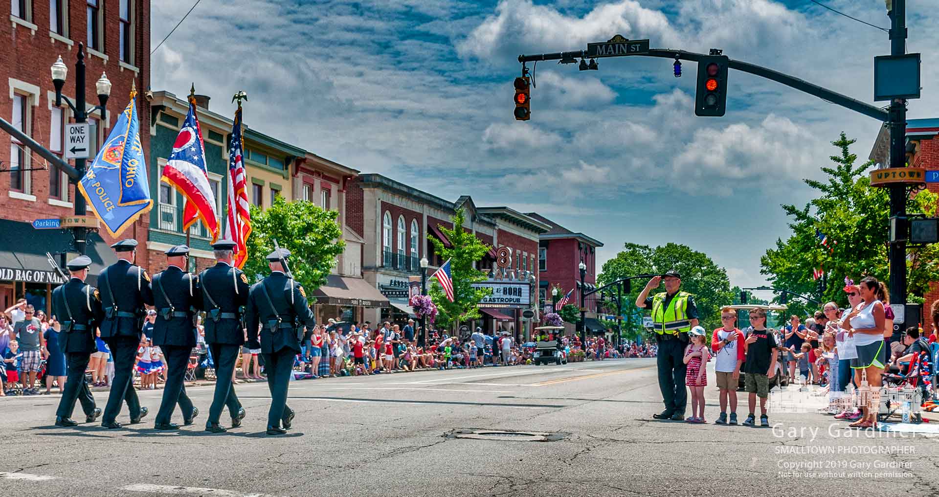 Westerville Reserve Officer Ted Bretthauer salutes as he stands with his three young charges as the police department Honor Guard passes at the lead of the 4th of July parade through Uptown Westerville. My Final Photo for July 4, 2019.