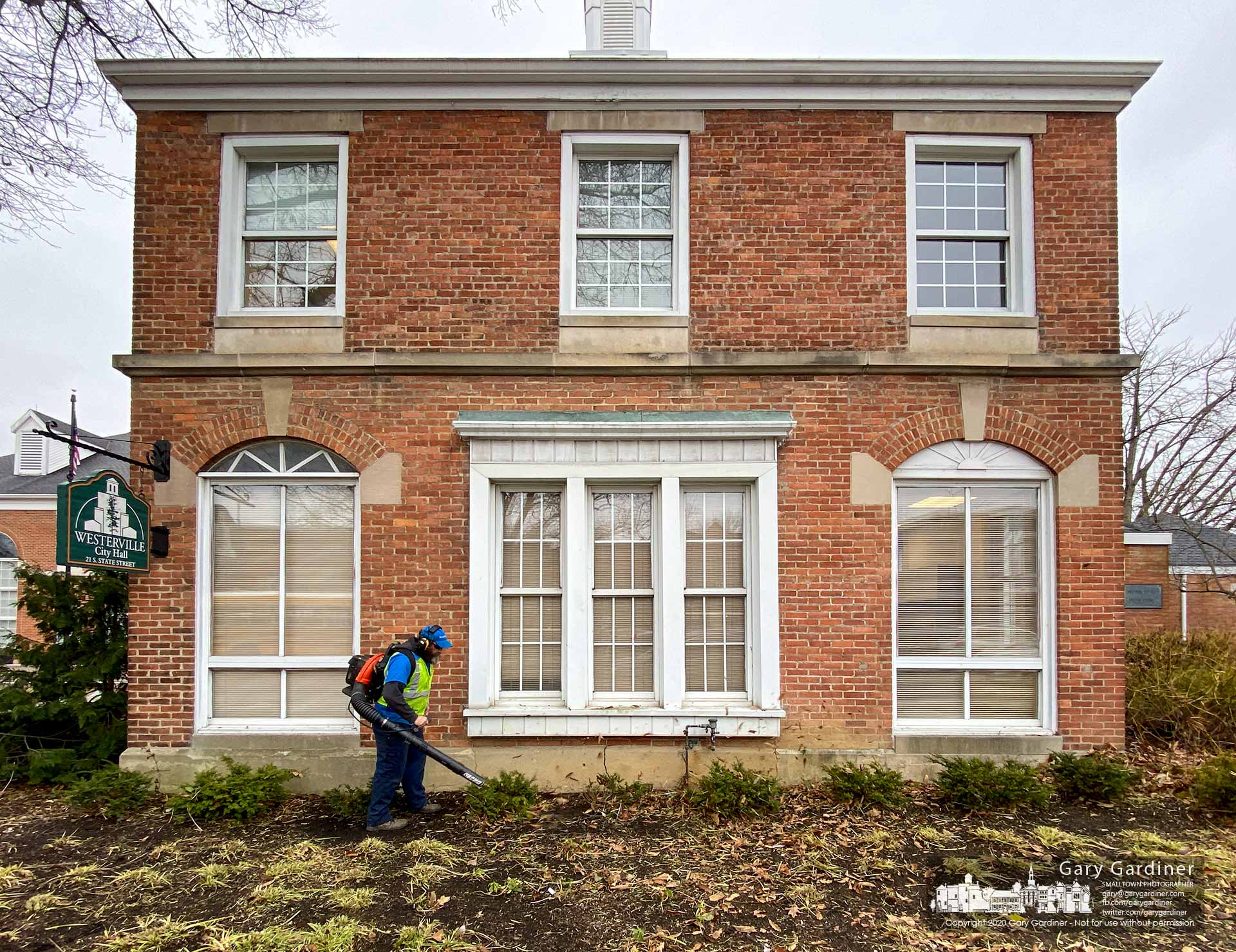 A landscaper clears leaves and garden debris from the front of city hall where a larger crew duplicated the work on other sections of the building and parking lot. My Final Photo for Jan. 29, 2020.
