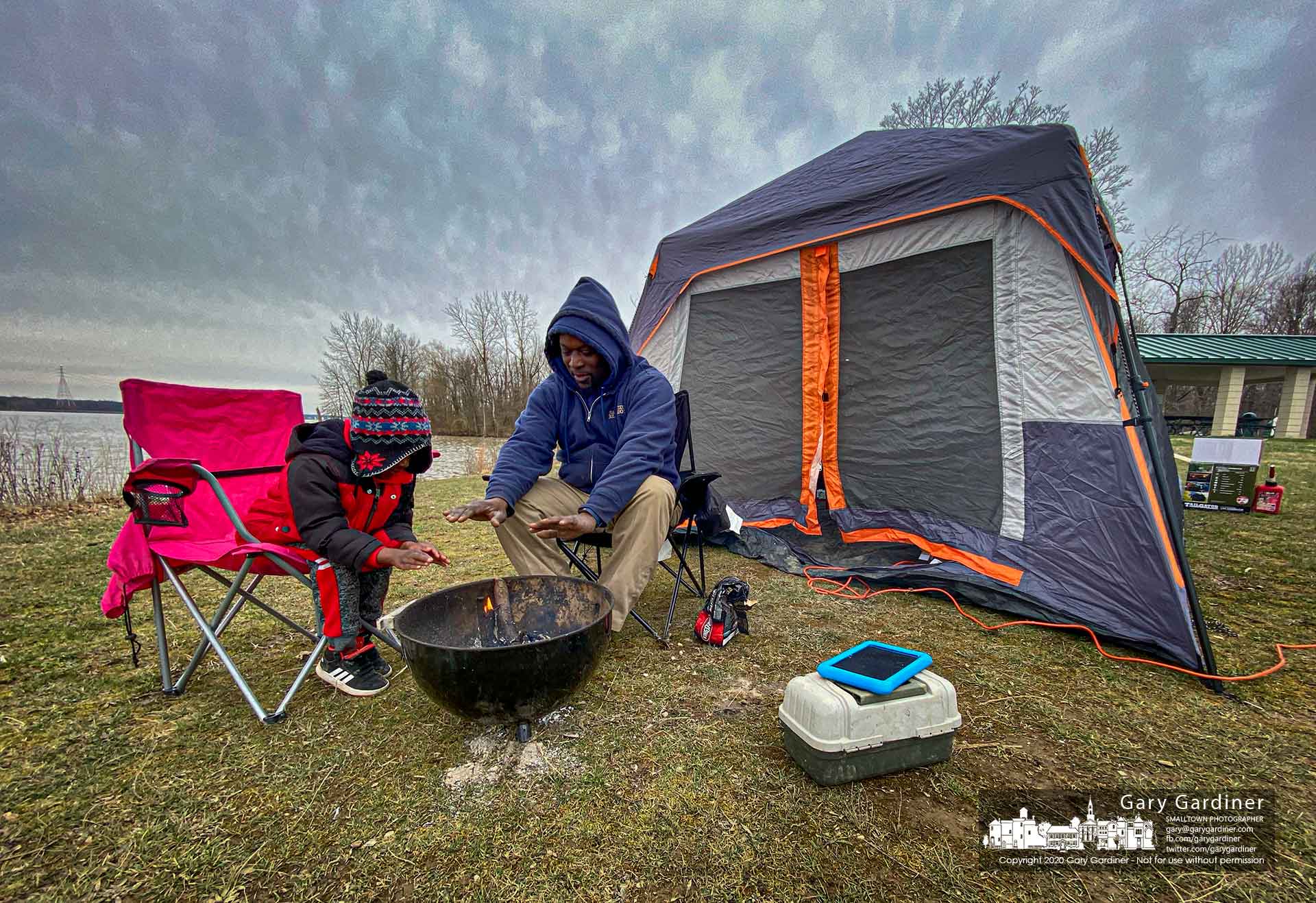Father and son warm their hands over a small fire they built while pitching the family's tent at Red Bank Park on an outing during the pandemic. My Final Photo for March 22, 2020.