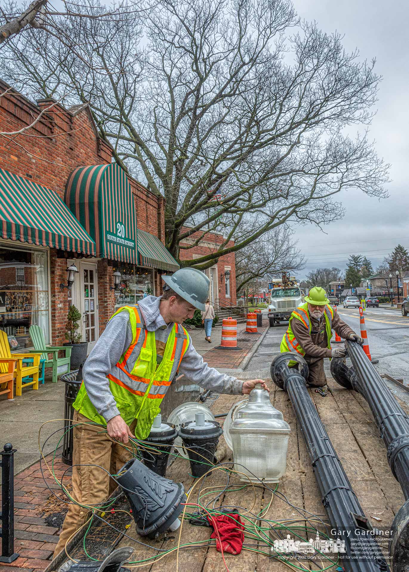 A crew removes street lamps near the oak tree between Java Central and the Westerville Police detective bureau as the first step in creating a new walkway that will protect the exposed roots and trunk of the tree when the Uptown improvement project is complete. My Final Photo for March 3, 2020.