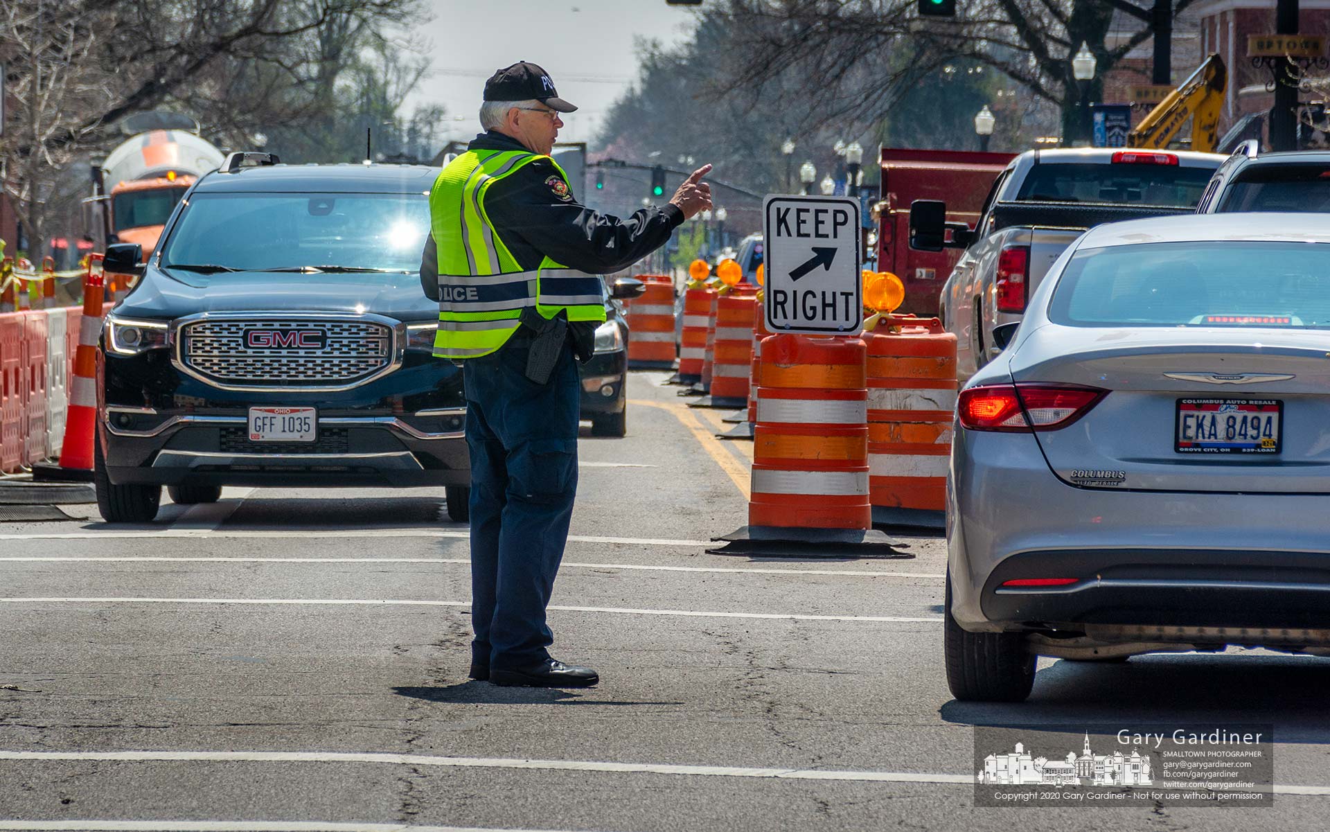 A Westerville Reserve Police Officer stands at the center of the intersection of State and Main Streets to direct traffic while electricians rewire the traffic signals. My Final Photo for April 8, 2020.