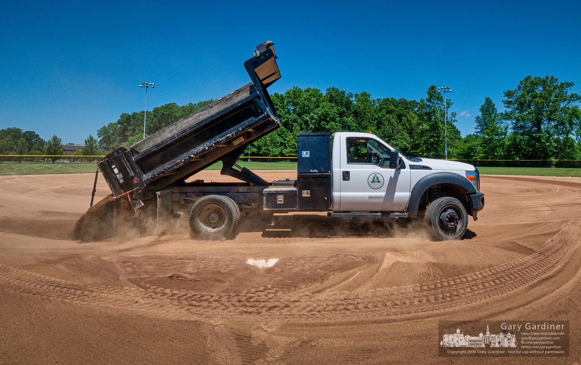 A Westerville Parks and Recreation crew spreads infield dirt on the fields at Hoff Woods Park as it prepares for upcoming softball tryouts and tournament. My Final Photo for July 1, 2020.