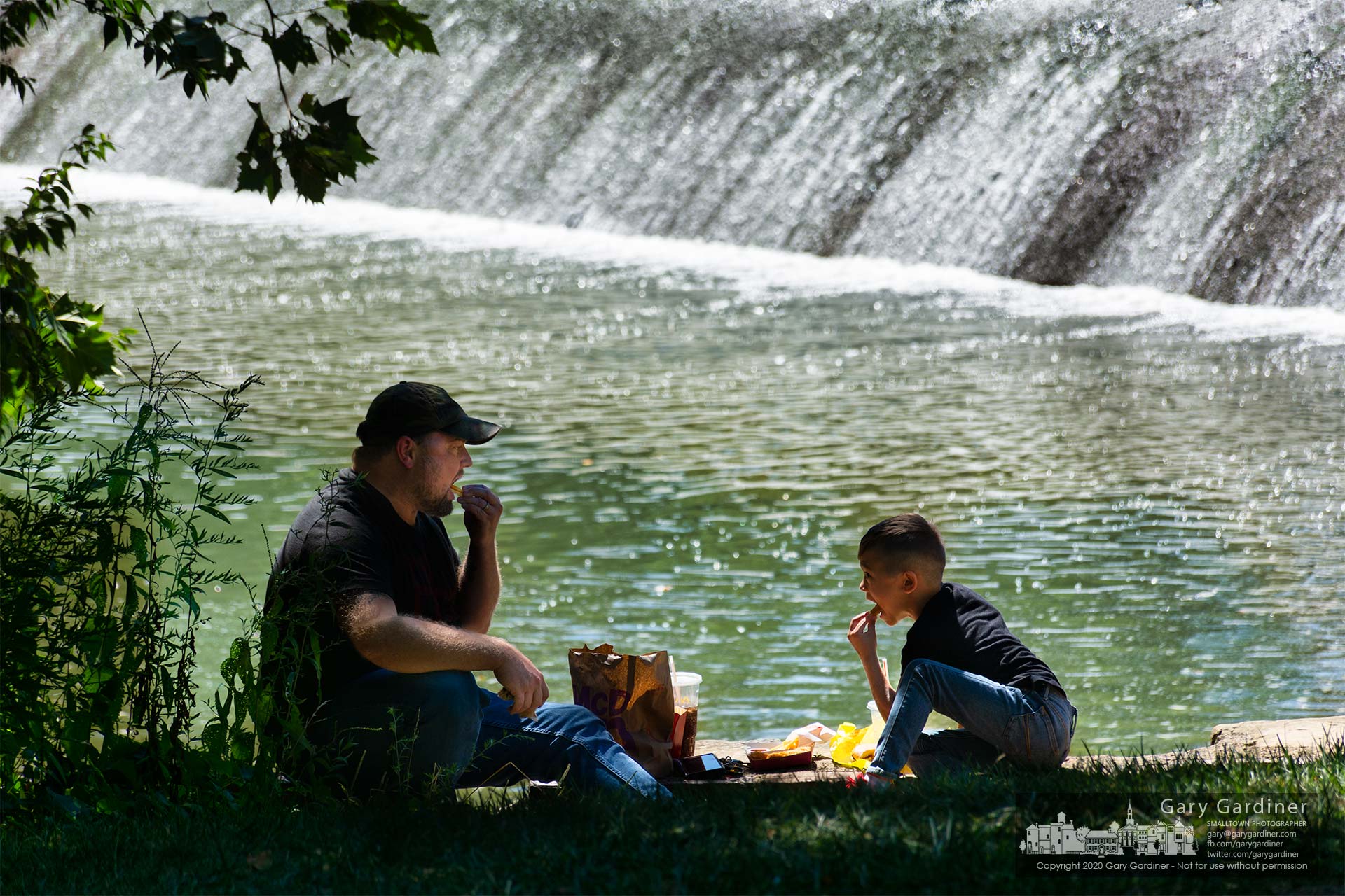 A father and son enjoy their fast food meal on the concrete abutment at the spillway in Alum Creek at Alum Creek Park North in Westerville. My Final Photo for Aug. 20, 2020.