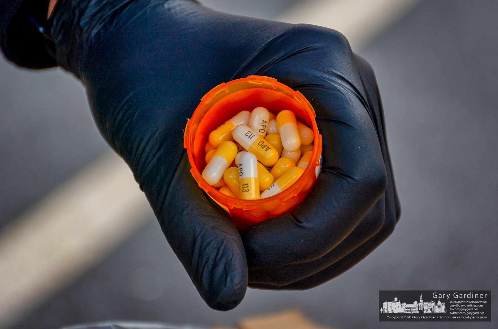 A gloved Blendon Township police officer prepares to drop a bottle of drugs into a holding container for disposal during Drug Disposal Day. My Final Photo for Oct. 24, 2020.