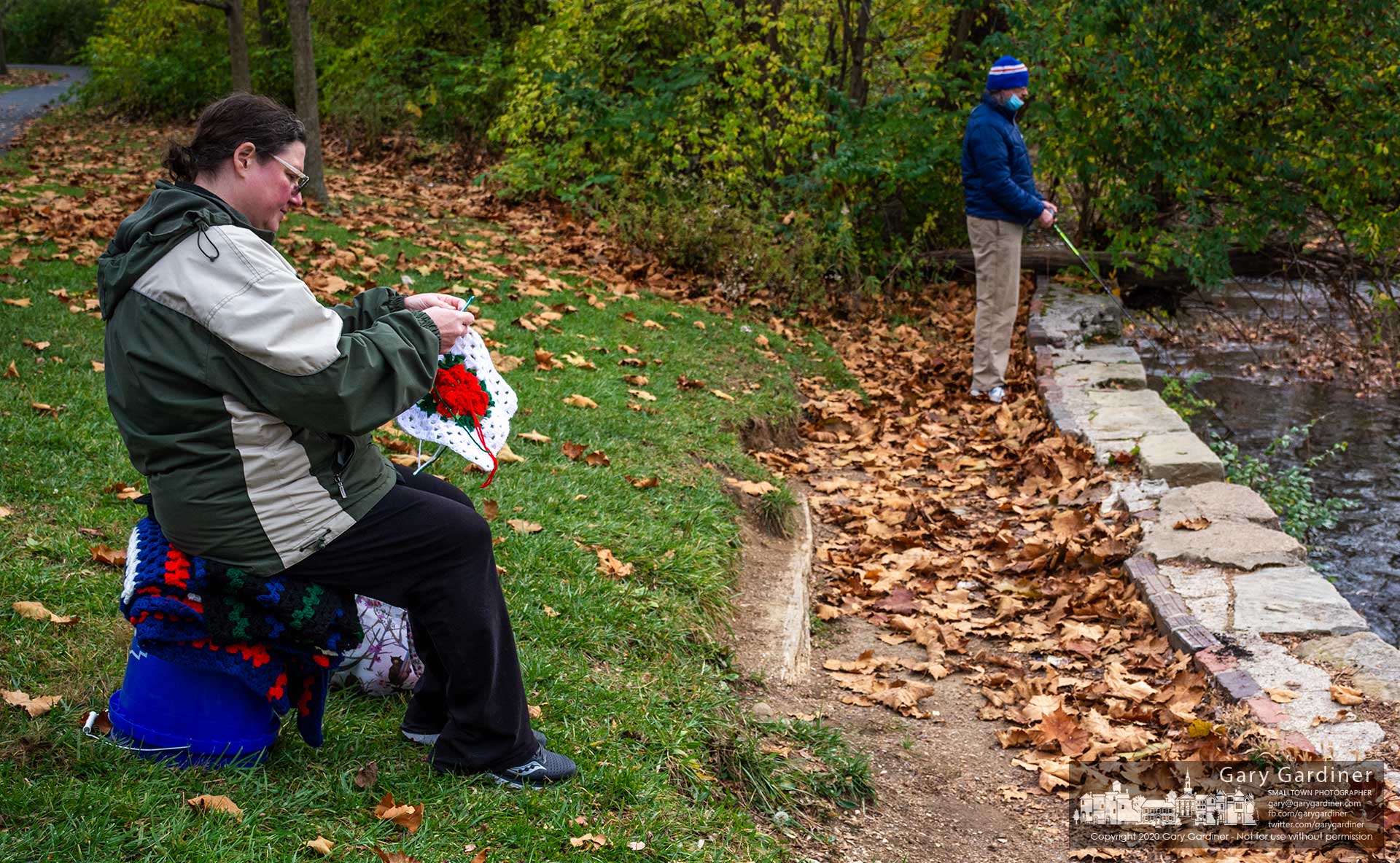 A woman crochets while her husband tries his luck and skill at fishing below the lowhead dam at Alum Creek Park North. My Final Photo for  Nov. 14, 2020.