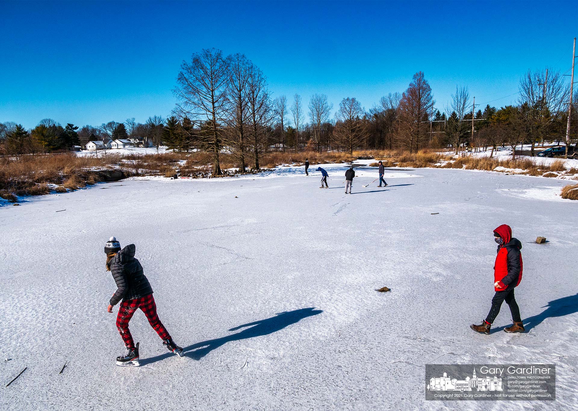 Groups of youngsters skate and play hockey on the thick ice covering the inches of water on the wetlands at Highlands Aquatic Center. My Final Photo for Feb. 7, 2021.