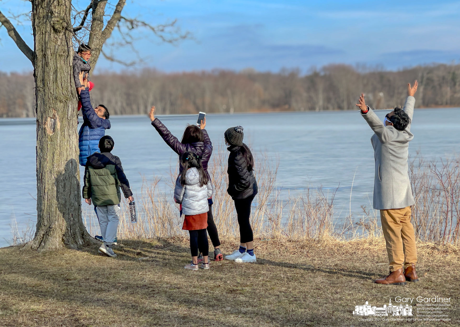A father lifts his son into the crook of a tree as his family urges the youngster to pose for a photo along the shoreline of Hoover Reservoir. My Final Photo for Feb. 27, 2021.
