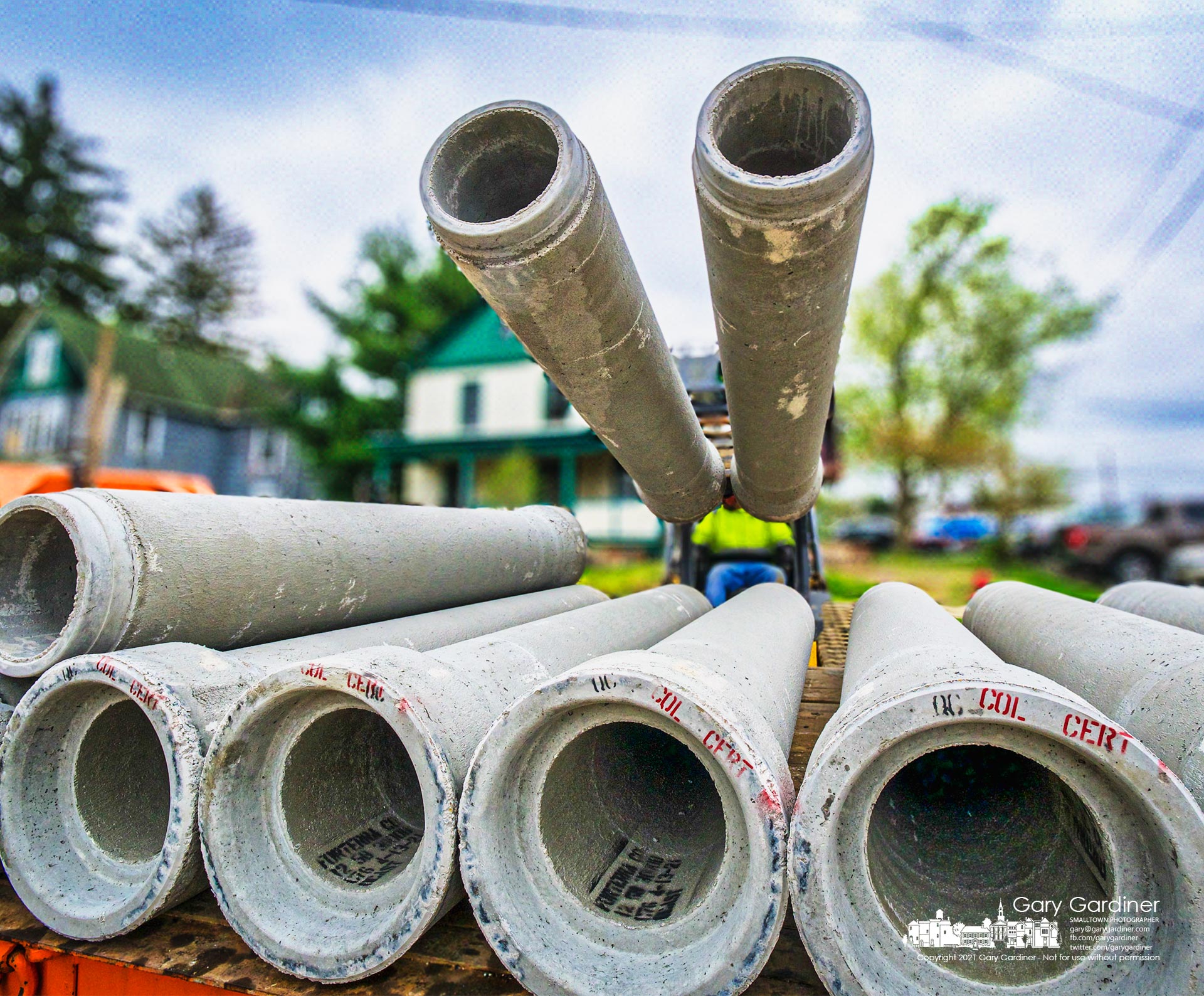 A truckload of concrete drain pipes are offloaded on West College where the first week of construction for the new parking lot behind city hall ended. My Final Photo for April 16, 2021.