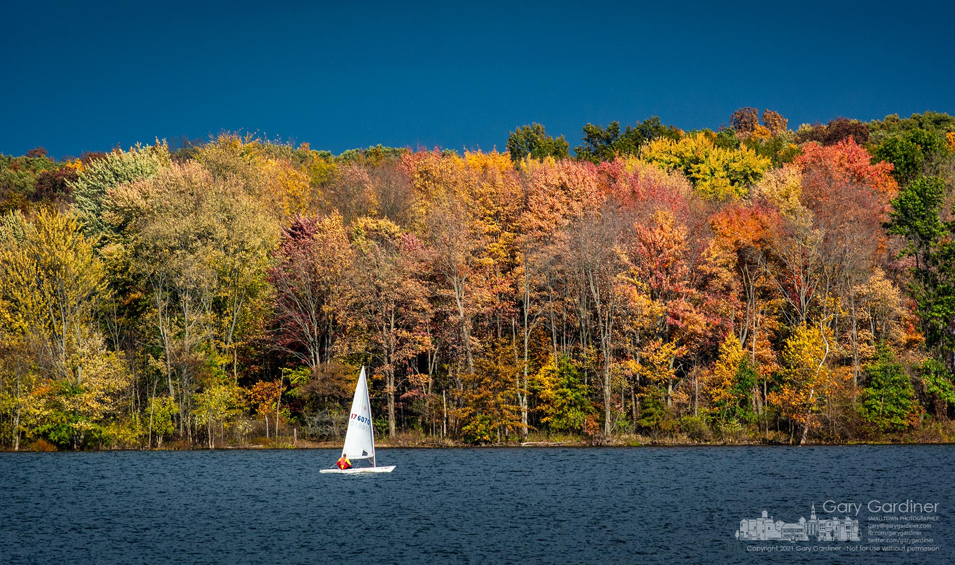 A sailor steers his single-sail craft along the gold-colored fall shoreline of Hoover Reservoir getting in a final sail for October. My Final Photo for Oct. 31, 2021.