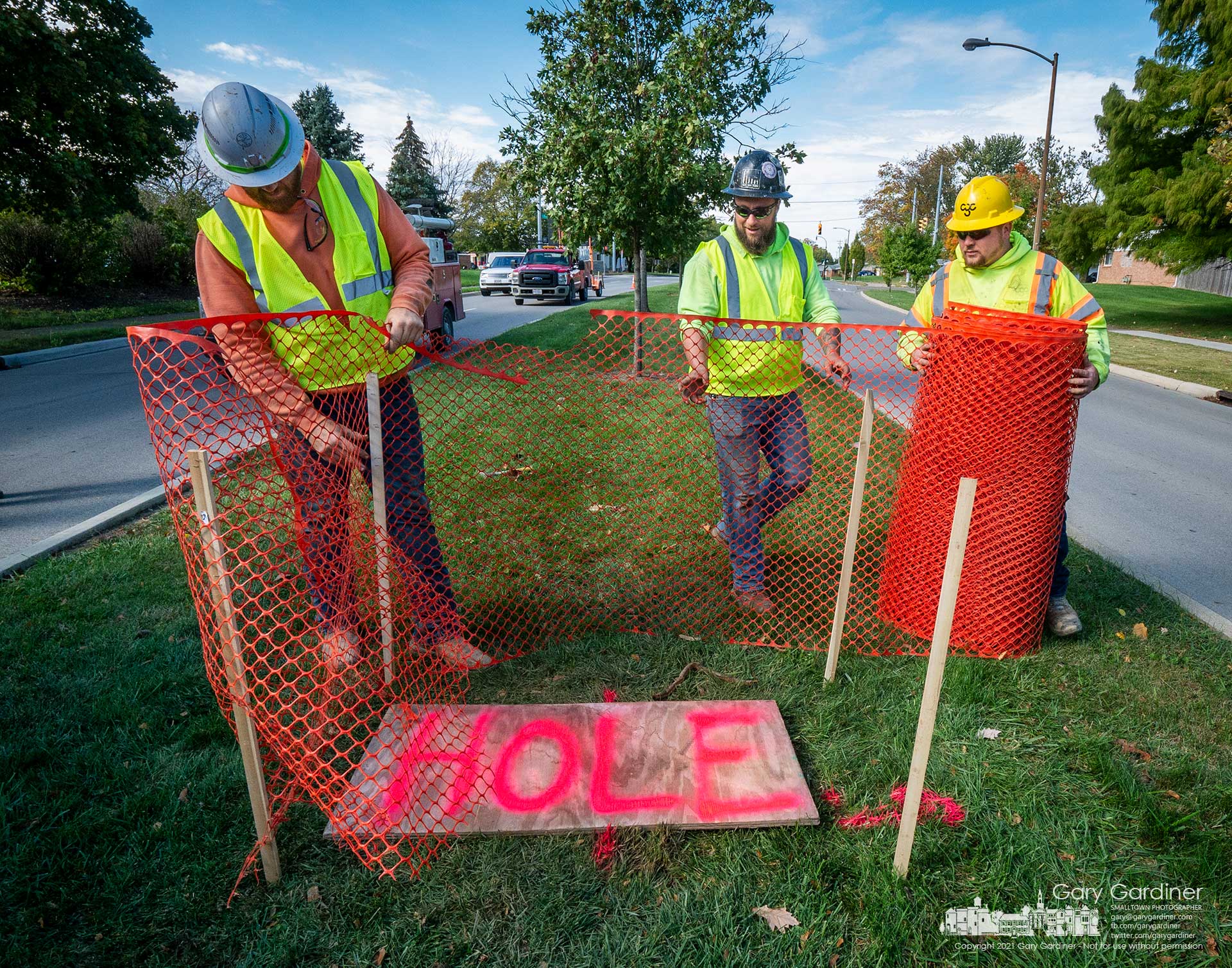 Workers mark the location of a hole bored into a median island on Huber Village Blvd. to mark underground utilities that may interfere with concrete pillars for new street lights. My Final Photo for Oct. 28, 2021.