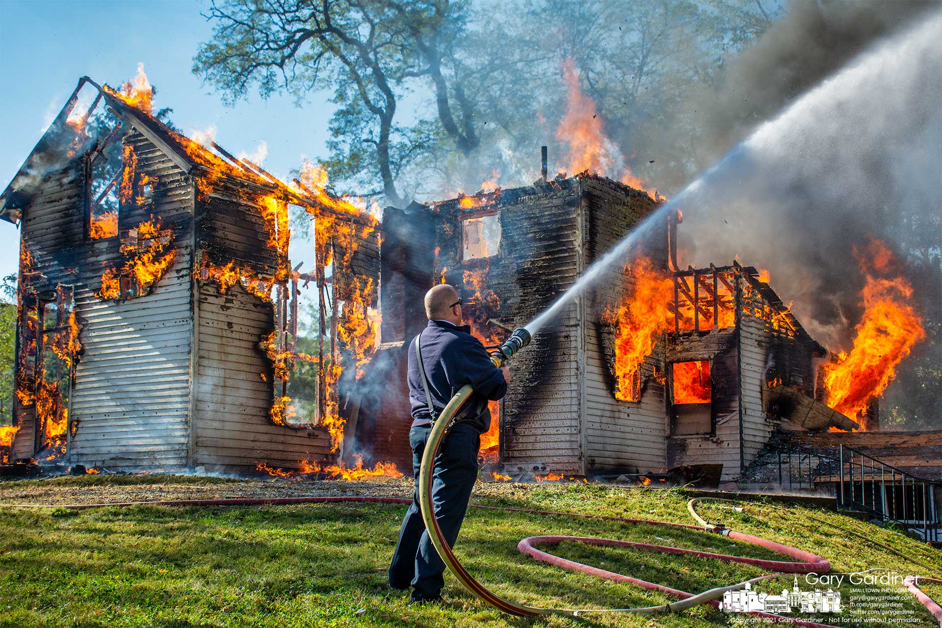 Westerville Fire Chief Brian Miller sprays water to protect nearby trees as a fire finishes burning a house that was used as training for Westerville and Genoa fire departments. My Final Photo for Nov. 6, 2021.