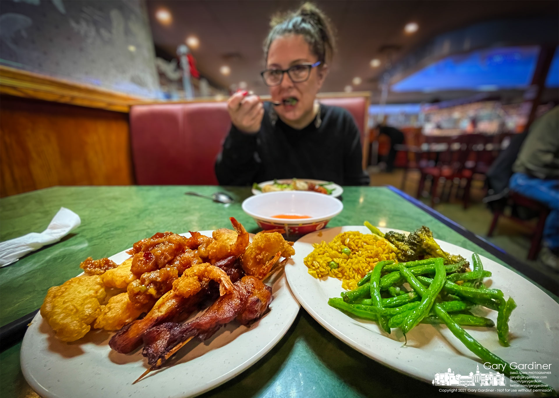 A woman sits down to a Chinese buffet meal for her Christmas dinner helping to somewhat solve the problem of her family not all being in the same place for Christmas. My Final Photo for Dec. 25, 2021.