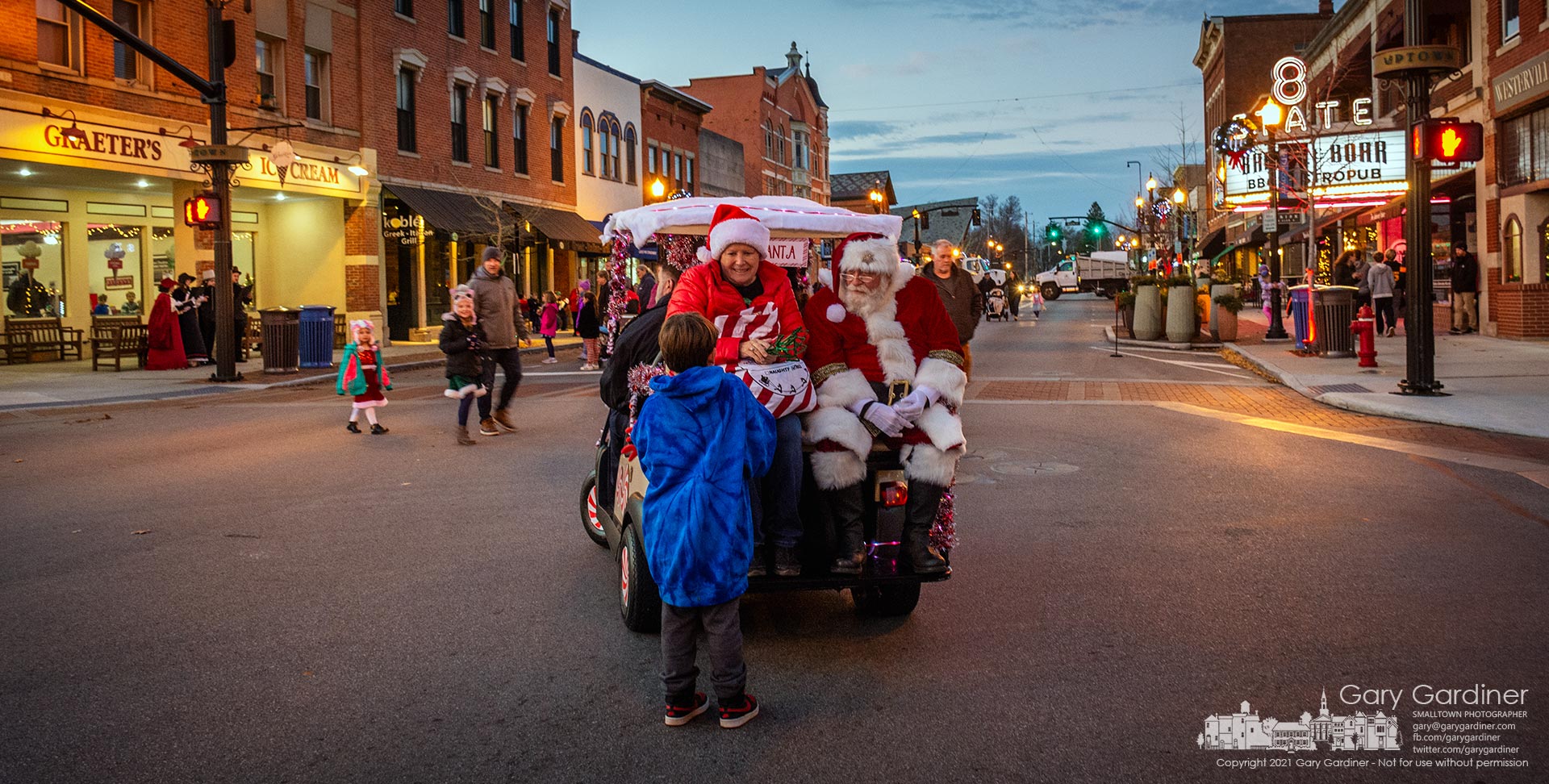 Westerville Mayor Kathy Cocuzzi accompanies Santa Claus who traveled in a golf cart instead of a sleigh and driven by the police chief instead of reindeer to visit with kids and their families after the tree lighting on State Street in Uptown Westerville. My Final Photo for Dec. 3, 2021.