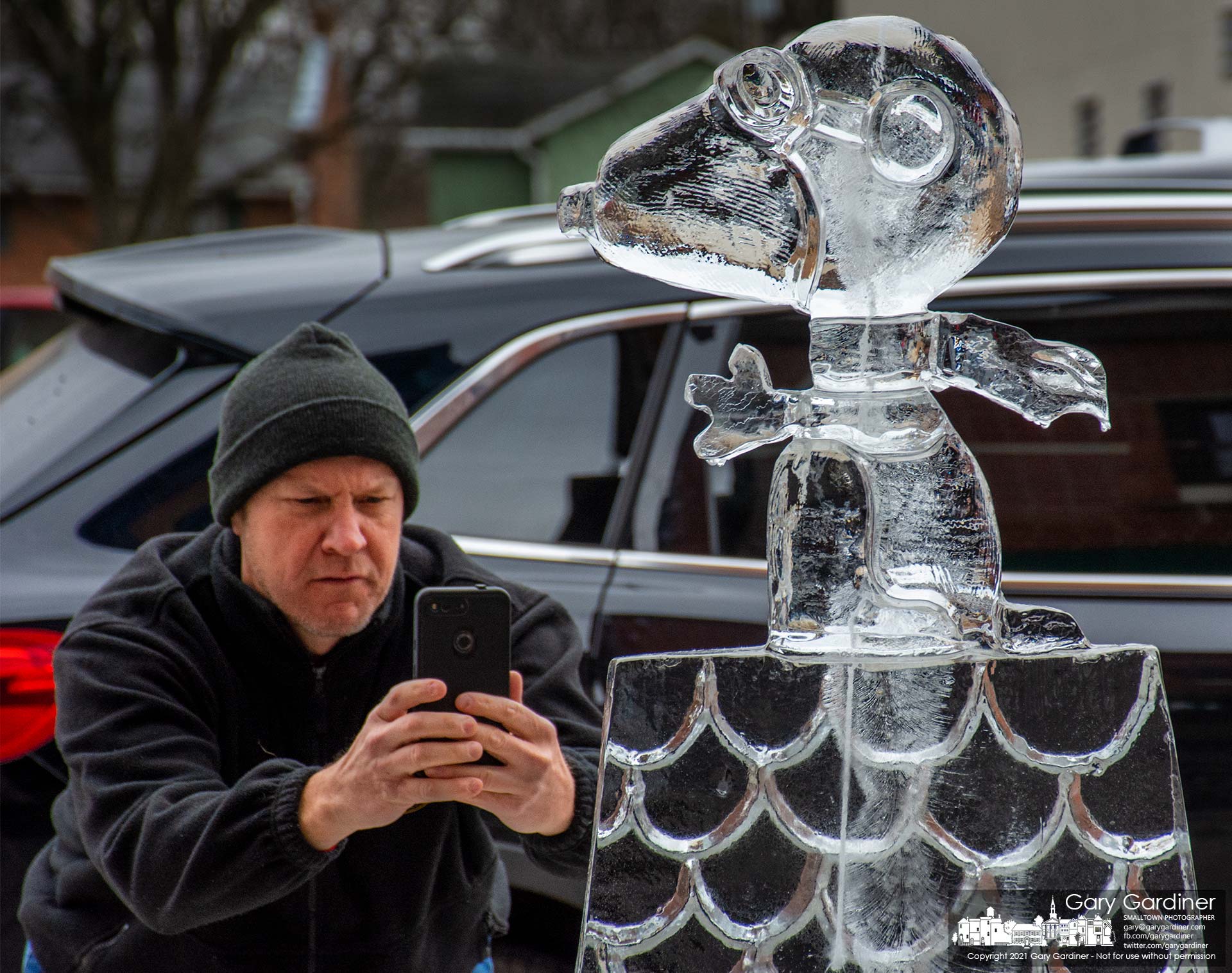 A man pauses on a Sunday walk in Uptown Westerville to photograph a Snoopy ice sculpture, one of more than a dozen sculptures on display this weekend. My Final Photo for Dec. 19, 2021.