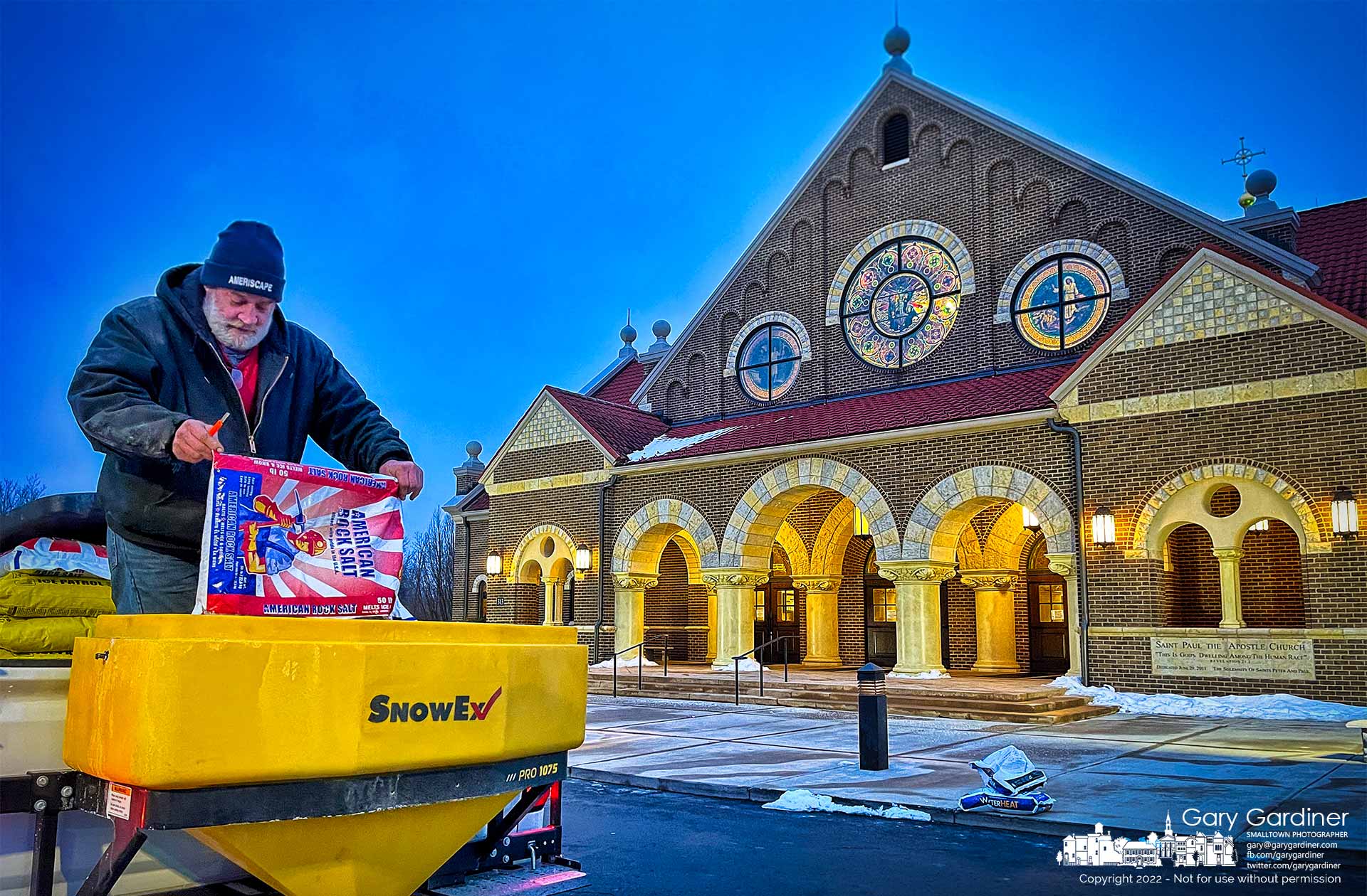 A worker loads salt into a spreader in front of St. Paul the Apostle Catholic Church in preparation for clearing snow and ice before the first Mass on Sunday. My Final Photo for Jan. 23, 2022.