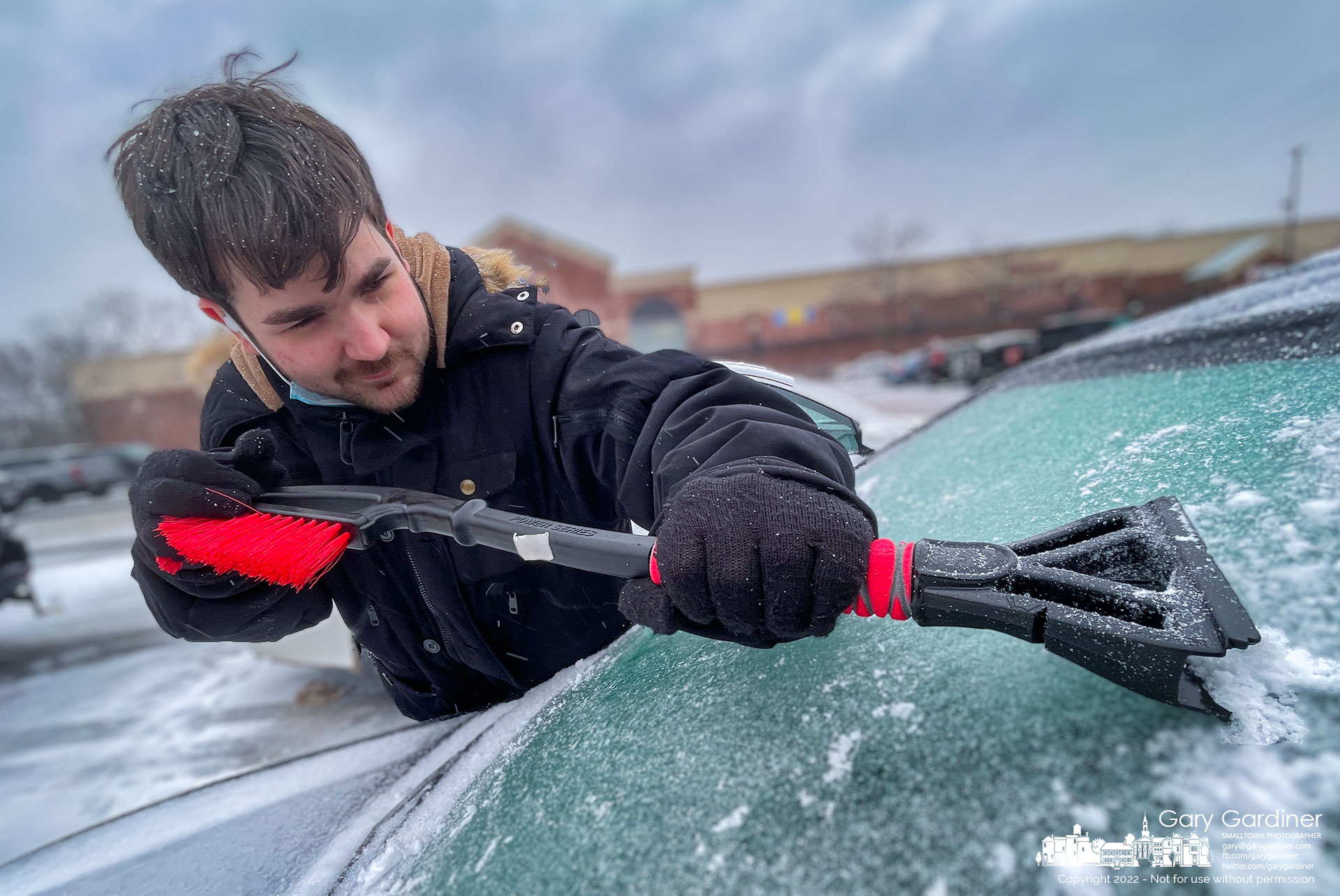 A man struggles to scrape away a layer of ice that collected on his car while he worked the early morning shift. My Final Photo for Feb. 3, 2022.