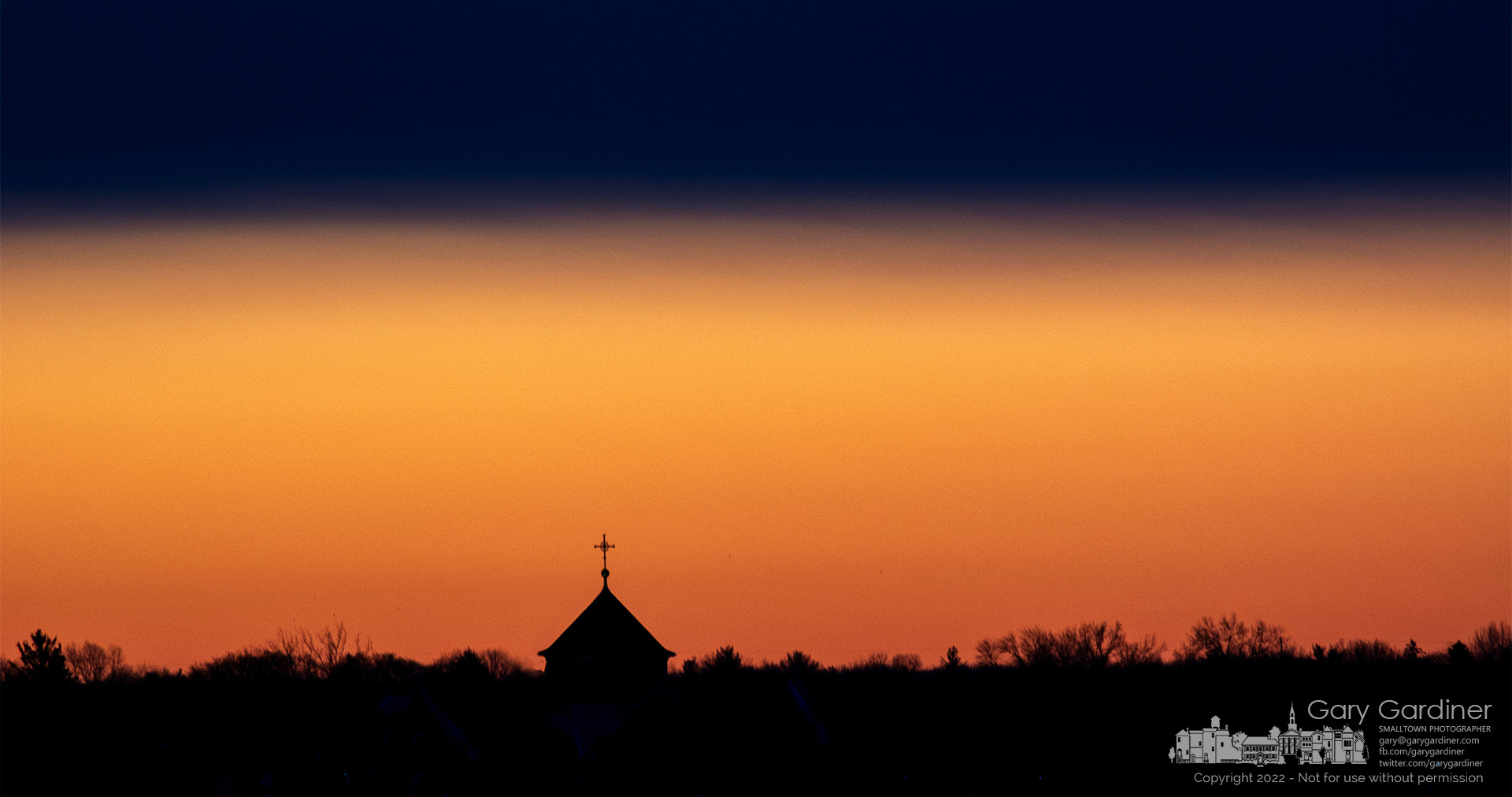 The steeple at St. Paul the Apostle Catholic Church stands above the treeline as the first light of day brightens the horizon minutes before sunrise. My Final Photo for March 13, 2022.