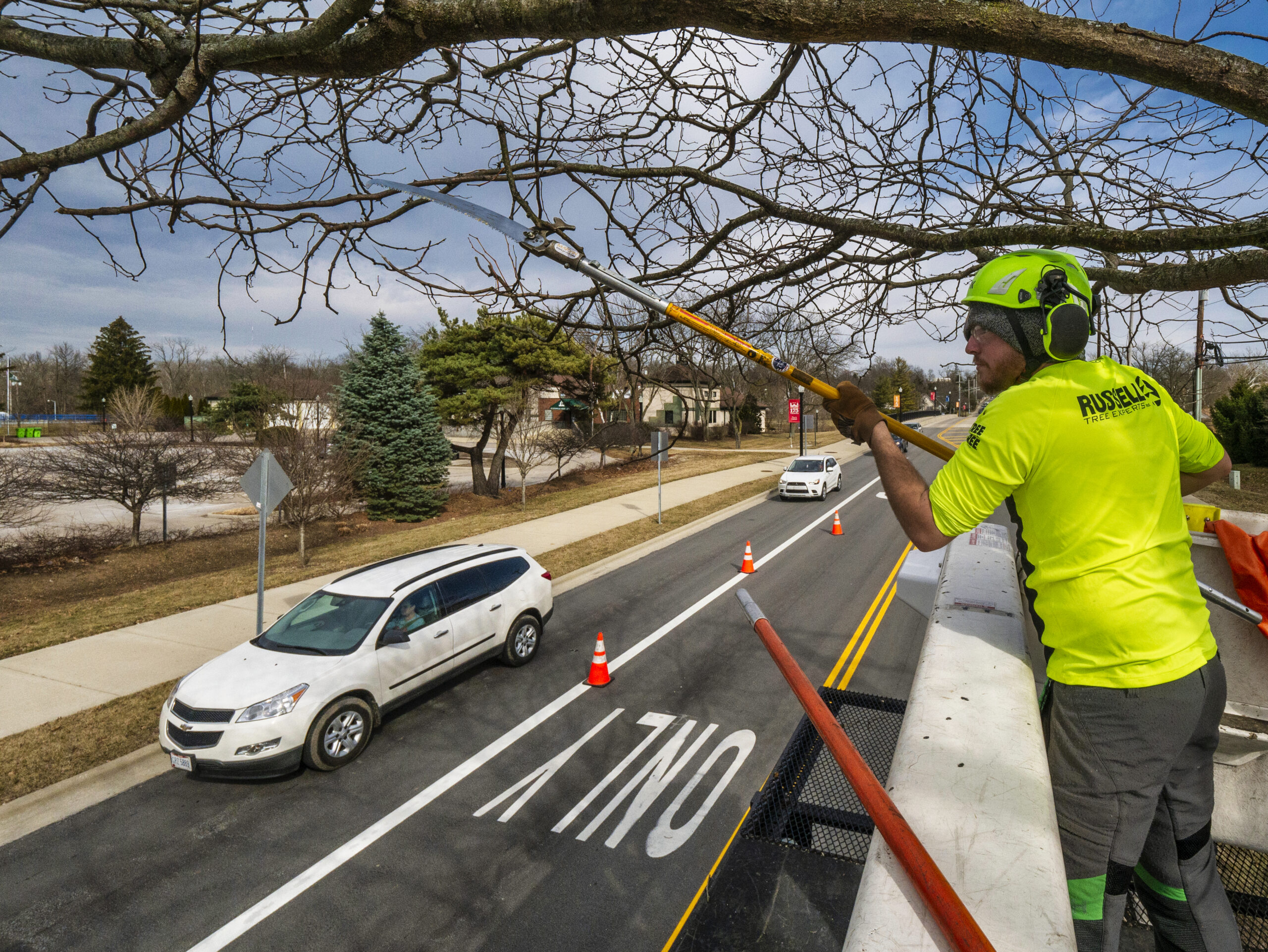A tree trimmer reaches stretches cut away a dead, damaged, or disruptive branch from a tree near the bridge over Alum Creek on West Main Street. My Final Photo for March 1, 2022.