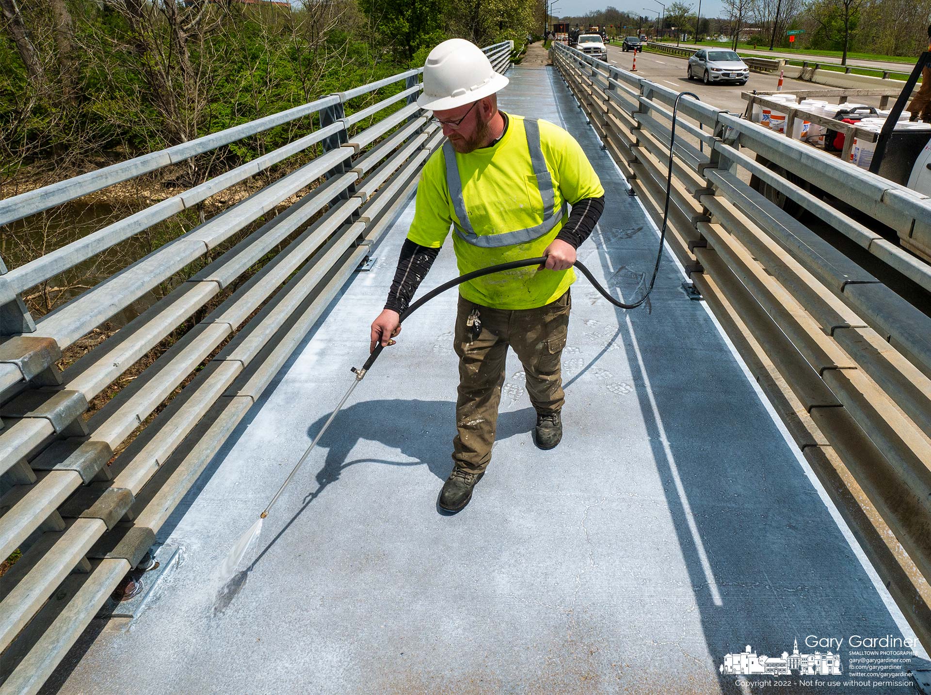 A contractor sprays sealant on the concrete sidewalk on the bridge crossing Alum Creek on Polaris Parkway after removing parts of the surface that needed repairs. My Final Photo for April 28, 2022.