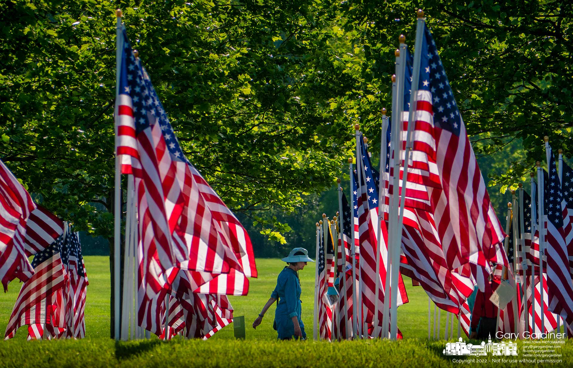 A woman walks through a partially shaded section of the Field of Heroes in Westerville where 3,000 American flags are erected honoring personal and military heroes. My Final Photo for May 29, 2022.