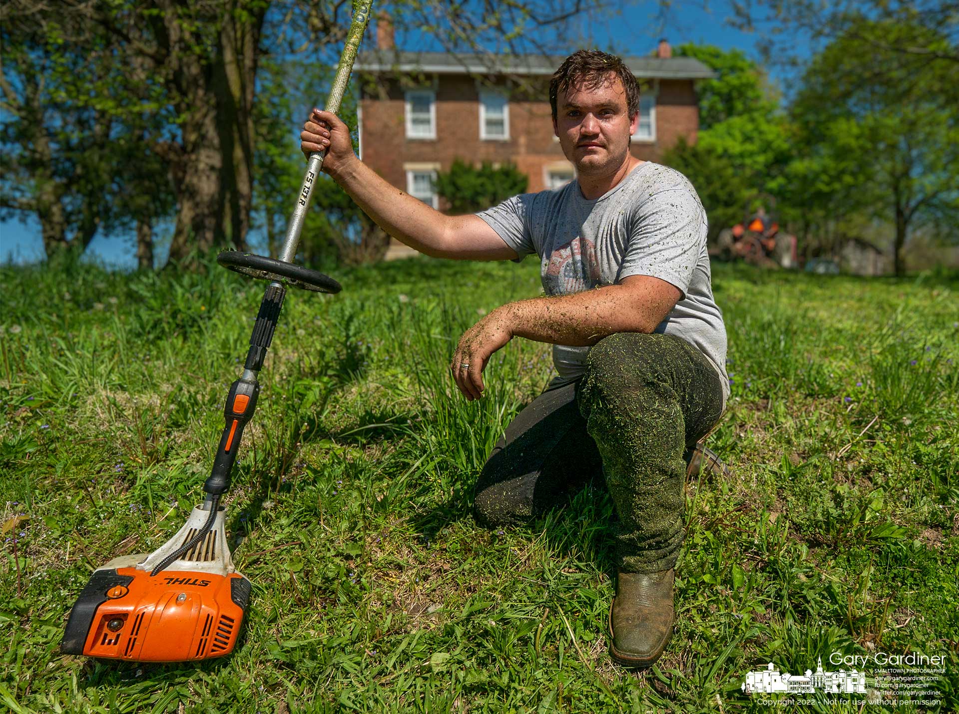 Brandon Rogers, a recent medical school graduate, kneels with the weed trimmer he's using to clear grass around sections of the Sharp Farm on Africa Road where the open fields are used to grow hay. My Final Photo for May 9, 2022.