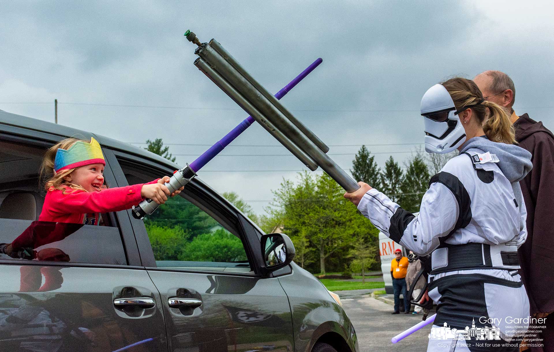 A youngster leans through the open window of her parent's car using her lightsaber to battle Imperial Stormtroopers at the W.A.R.M. food dropoff at Highlands Park. My Final Photo for May 4, 2022.