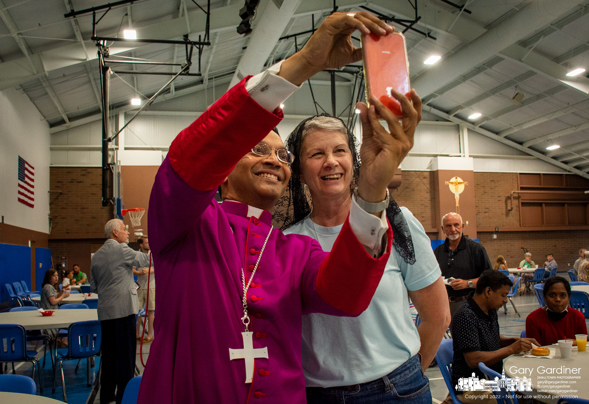 Columbus Bishop Earl Fernandes uses a parishioner's phone to shoot a selfie with her during St. Paul's donut Sunday gathering after Mass. My Final Photo for June 26, 2022.