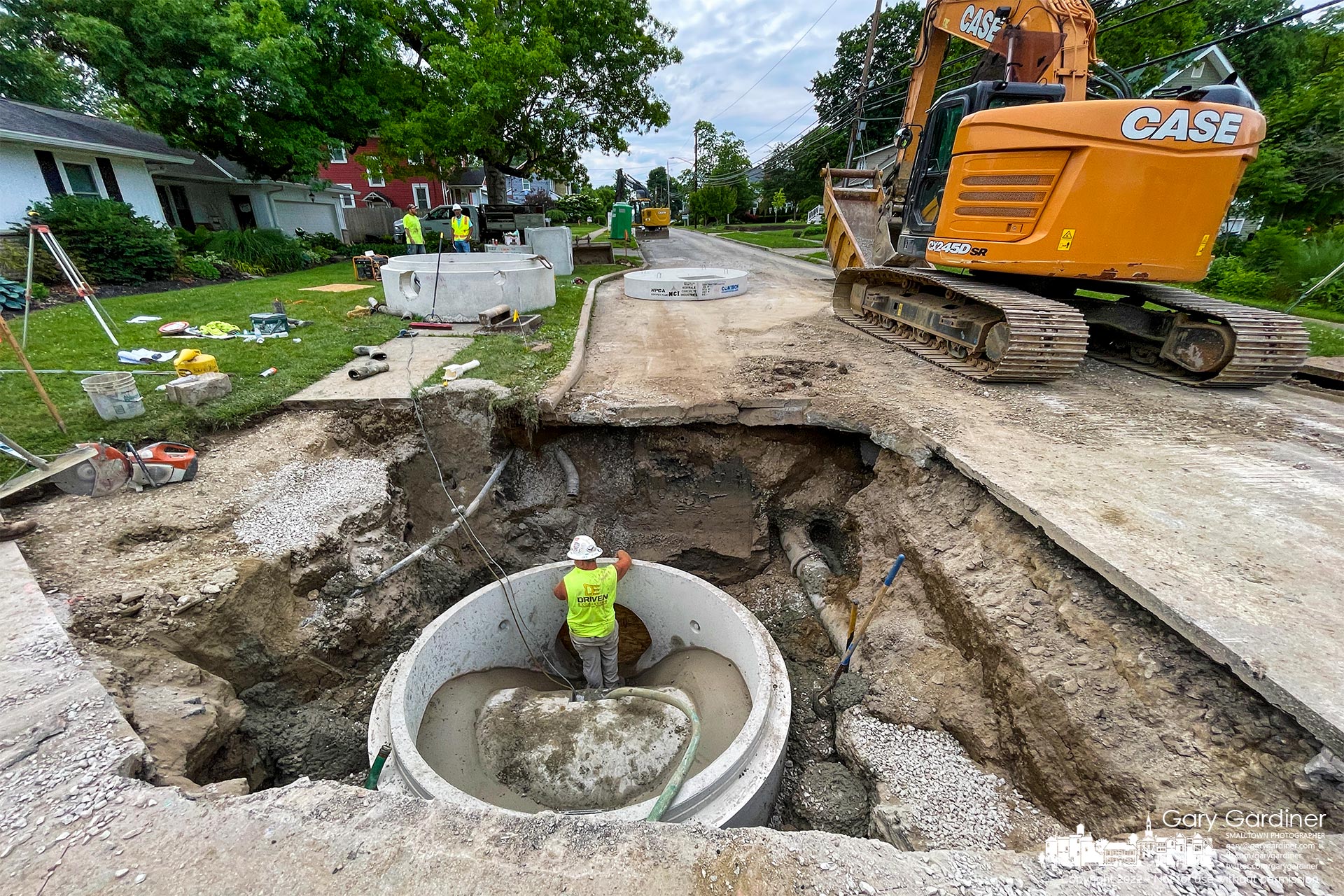 A concrete manhole base is set over an existing storm drain before the old drain is cut open to create a connection for new storm sewers being laid on East College near Otterbein Ave. My Final Photo for June 8, 2022.