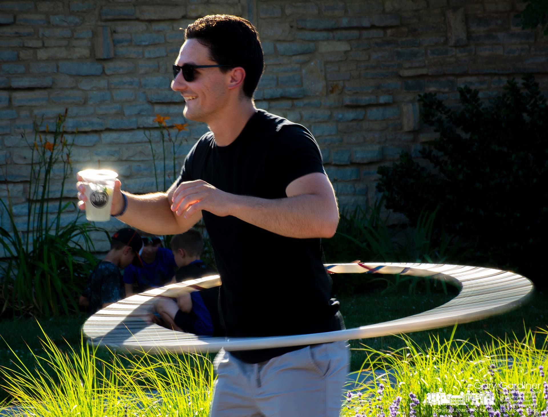 A man, DORA drink in hand, shows his prowess at spinning the hula hoop during Fourth Friday in Uptown Westerville. My Final Photo for June 24, 2022.