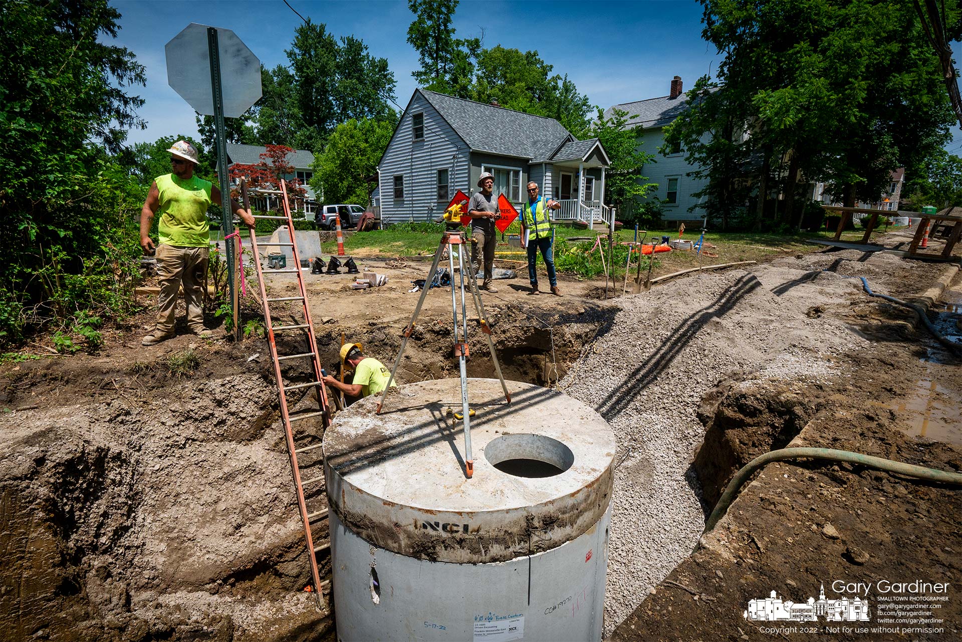 Workers and a city planner check over the installation of a new storm drain manhole near water mains on East College where utility construction has interrupted traffic and access to parts of the area. My Final Photo for July 7, 2022.
